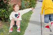 © Pavel Losevsky - Little cute girl sits on floor and reaches out to boy going past on street background