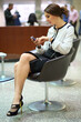 The woman with the phone sitting on black chair in the lobby of the business center