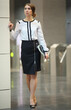 The woman in white blouse and black skirt with the folder standing in the lobby in front of turnstiles in business center