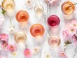 Top view of various wine glasses surrounded by delicate spring flowers on a marble background, symbolizing a refined tasting event