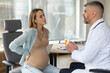 © Home-stock - Sick pregnant lady touching back during meeting with her doctor in clinic, male therapist consulting expectant woman suffering lower back pain
