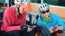 Senior and mature woman take a break while biking to look at a map on their phone for directions.