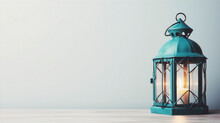 A Teal Blue Metal Lantern With A Burning Candle On A Wooden Table Against A Pale Blue Background.