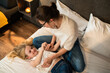 Mother and child girl in bedroom cuddling on cozy warm comfortable bed in hotel room