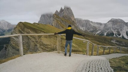 Wall Mural - Man traveler stands on the observation deck in the national park of mountain Seceda in the Dolomites. Alps mountains in autumn or winter. Beautiful alpine mountains in Italy. Seceda, one of the most