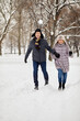 © Pavel Losevsky - Smiling man and woman run holding hands in winter snow-covered park.