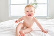 © Louis-Paul Photo - Baby boy in diaper on white sunny bedroom. one years child relaxing in bed.