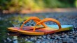 Colorful flip-flops on a wet pebbly surface in sunlight