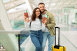 Happy young couple in airport holding passports and boarding passes