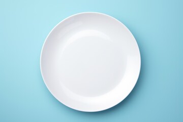 Poster - A simple white plate on a blue surface. Perfect for food or kitchen-related designs