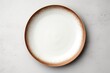 A simple white plate with a brown rim on a table. Suitable for food and dining concepts