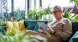 © pikselstock - Senior man using digital tablet while sitting on sofa in living room at home