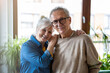 © pikselstock - Portrait of happy senior couple embracing each other in living room at home