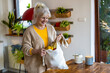 © pikselstock - Senior woman holding reusable bag with groceries in kitchen