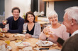 © Mikolette Moller/peopleimages.com - Smile, cheers and family at dinner in dining room for party, celebration or event at modern home. Happy, bonding and group of people enjoying meal, supper or lunch together with wine at house.