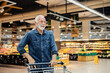 © Jelena Stanojkovic - Cropped shot of mid 60's handsome man walking through supermarket aisle and buying some food during weekly grocery shopping.