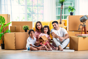 Happy Indian family unpacking boxes at new home