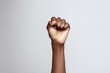 A raised clenched fist, symbolizing strength, resistance, and solidarity, set against a plain white background. Empowerment Symbol: Raised Fist Against White