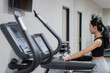 © wdnld - Woman using elliptical cross trainer in gym modern fitness center room