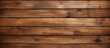 Closeup shot of a brown hardwood plank wall with a blurred background. The wood stain highlights the rectangle pattern of the flooring