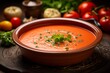 Juicy gazpacho in a clay dish against a natural brick background