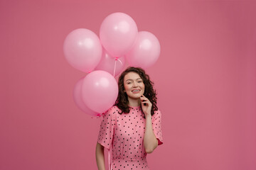 Wall Mural - pretty young woman posing isolated on pink studio background with pink air balloons