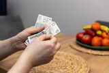 Fototapeta  - Mężczyzna liczący banknoty o nominałach 20, 50 oraz 10 złotych ilustruje koncepcję znaczących wydatków wobec wysokości wynagrodzenia, z uwzględnieniem wysokiej inflacji oraz rosnących rachunków 