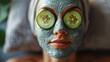 Close-Up of Woman's Relaxing Spa Experience with Facial Clay Mask and Cucumber