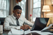 © romanets_v - A young businessman working at home with a laptop and papers on his desk, suggesting the flexibility and commitment of remote or home-based work