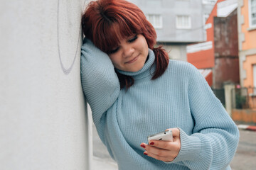 Wall Mural - teenager girl leaning on the wall with the phone