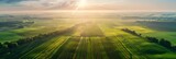 Fototapeta Młodzieżowe - Bird's eye view of agricultural cultivated seeded fields, farmland in the rays of the rising sun, banner