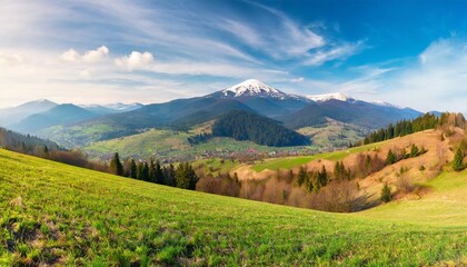 Wall Mural - panorama of mountainous rural landscape with village in the valley carpathian countryside scenery with arable on hills in front of borzhava ridge with snow capped top on a sunny morning in spring