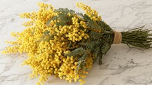 A Bunch Of Yellow Flowers Sitting On Top Of A White Marble Counter Topped With Green Leaves And A Twine Of Twine.
