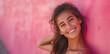 Junge hübsche Frau lächelt, Mädchen mit rosa Oberteil vor einer rosa Wand