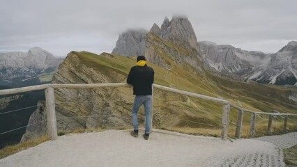Wall Mural - Man traveler stands on the observation deck in the national park of mountain Seceda in the Dolomites. Alps mountains in autumn or winter. Beautiful alpine mountains in Italy. Seceda, one of the most