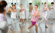 Young girls and boys repeat the movements of dance teacher, training in a spacious studio