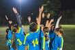 © PoppyPix - teenage footbal player girls heating up before match and holding hands in the air, team sport concept. High quality photo