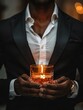 Handsome man holding elegant glass vessel with candle with lighted flame, wearing black suit and white shirt, wearing expensive watch, photograph of goods. Businessman, luxury, sensuality