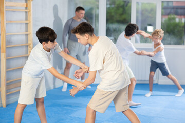 Wall Mural - Young children working in pair mastering new self-defense moves at modern gym