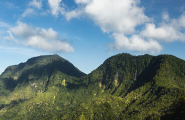 Wall Mural - Clouds drifting over the ridge of tropical mountains and hills covered in vegetation and trees in Bali. View from Lahangan Sweet viewpoint.