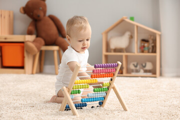 Sticker - Children toys. Cute little boy playing with wooden abacus on rug at home