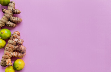 Wall Mural - Flat lay of fresh Curcuma roots and limes on a purple background with copy space on the right, ideal for healthy lifestyle concepts and nutrition-related design projects