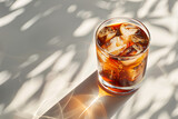 A refreshing iced americano in a transparent glass, casting a shadow on a patterned surface with light play.