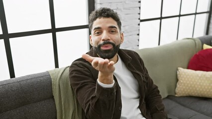 Canvas Print - Cheerful young man blowing a fun, love-filled kiss to the camera in a handsome, confident gesture from his cozy living room, home atmosphere adding to his lovely and sexy expression.