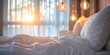 An inviting bedroom scene with rumpled white bedding and warm glowing hanging lights during a serene sunrise.