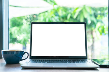 Wall Mural - Mockup of laptop computer with empty screen with coffee cup and smartphone on table of the coffee shop background,White screen