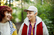 Cheerful pensioner female friends tallking and laughing in the autumn park.