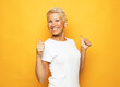 Senior happy woman showing thumbs up over yellow background.