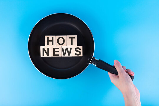 Frying pan with the phrase hot news made of wooden letters. News preparation concept. Isolate on white background