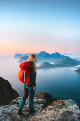 Wall Mural - woman with red backpack hiking in norway girl traveler on mountain cliff edge in lofoten islands tou